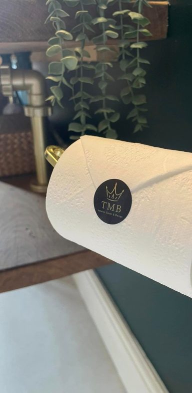 A picture of a rolled up toilet paper with the TMB design and clean sticker.